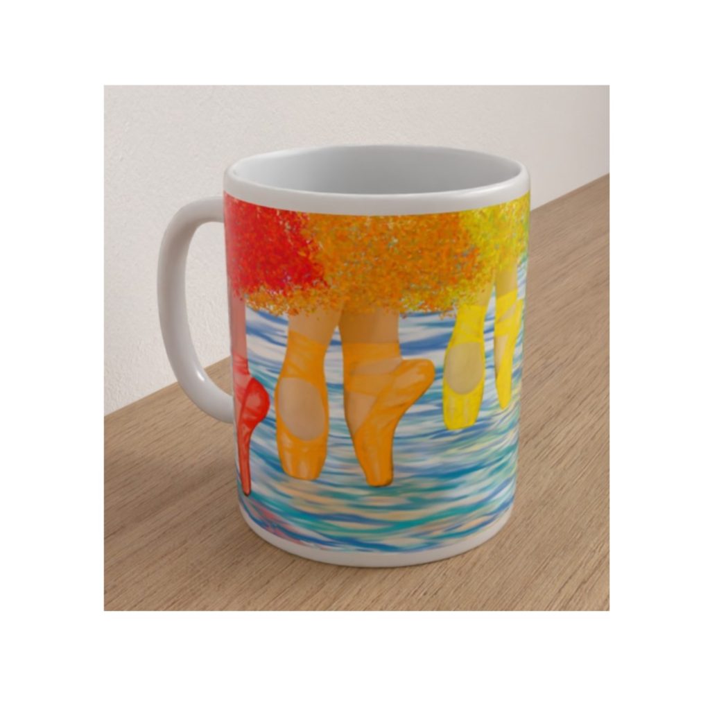 Angled view of the Ballet Shoes mug featuring orange and yellow ballet pointe shoes above shimmering blue water with colourful Skirts.