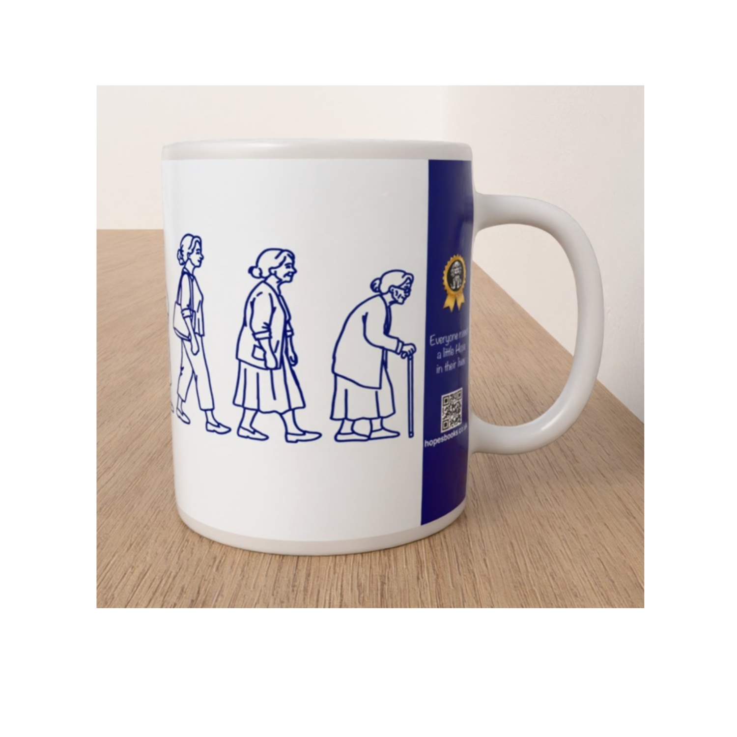 Side view of white Womanhood mug showing blue line drawings of elderly women and the Hope's Books branding panel.